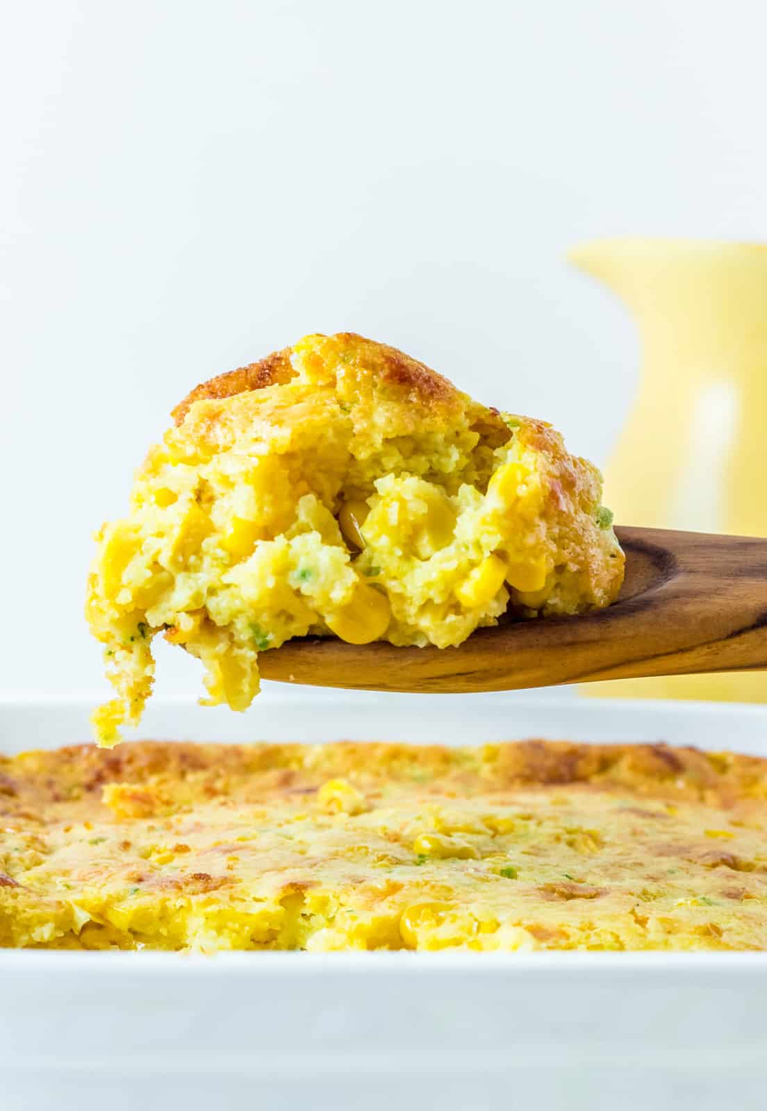 Jalapeno Honey Cornbread Casserole being lifted out of pan on wooden spoon.