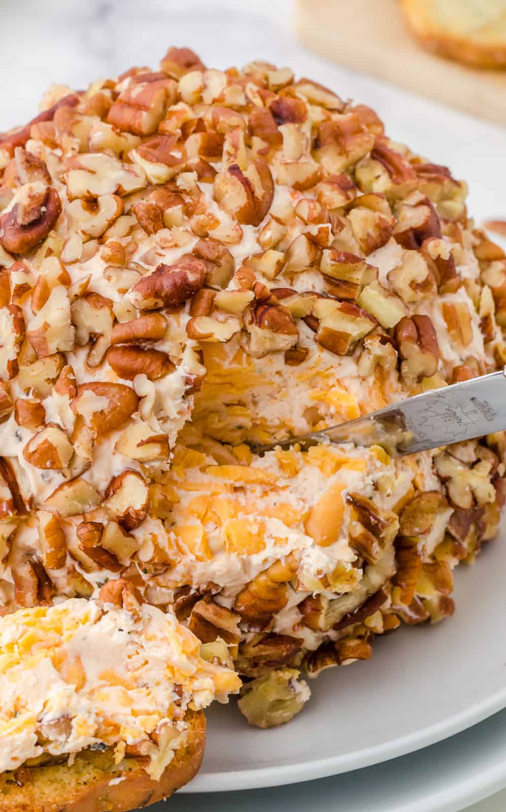 Close up of Sun-Dried Tomato Cheese Ball Recipe showing inside with knife.