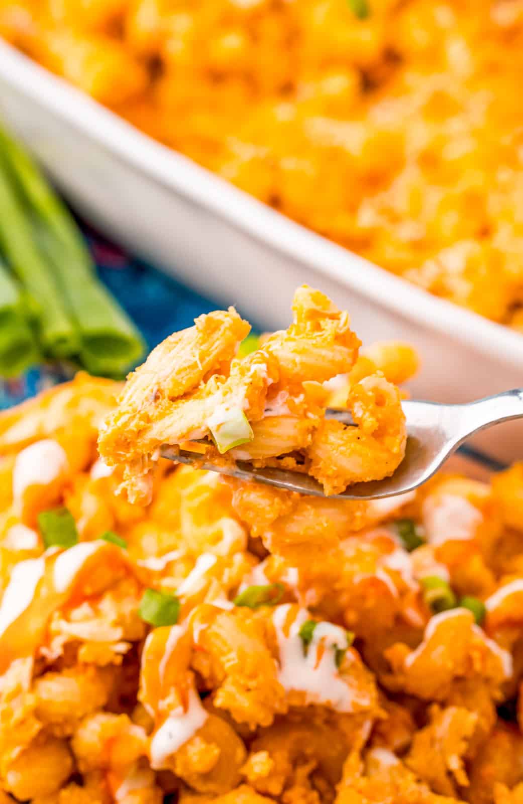 Fork holding up some Buffalo Chicken Mac and Cheese off plate.