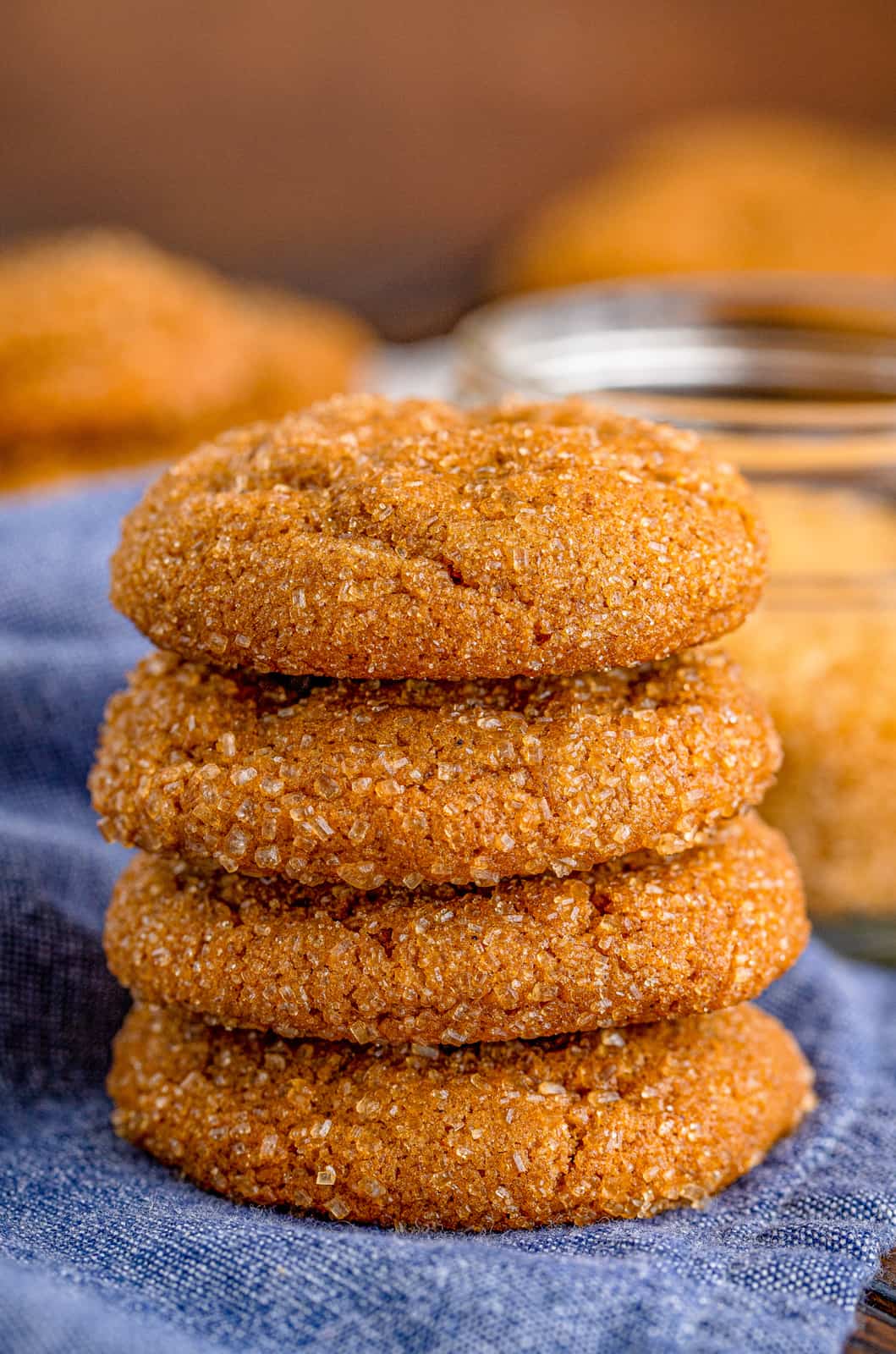 Four stacked Chewy Molasses Cookies on denim linen.