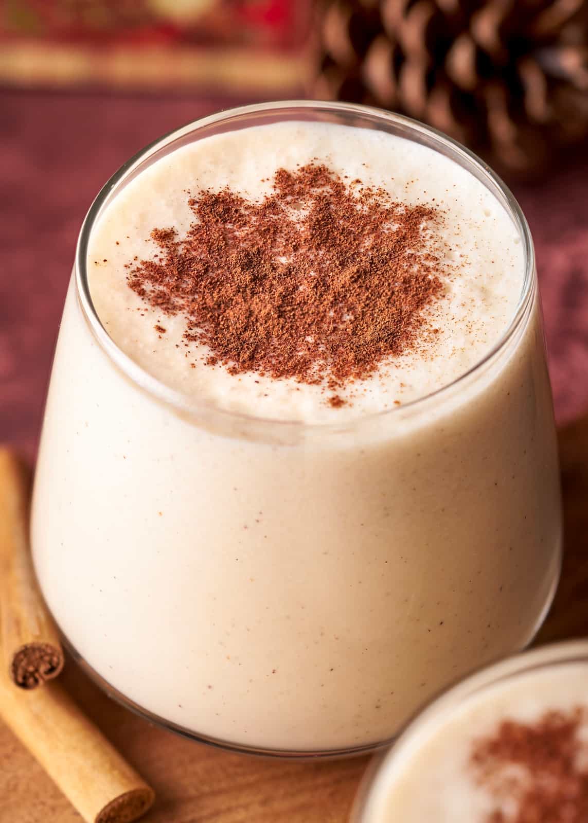 Glass of Coquito Recipe topped with cinnamon.