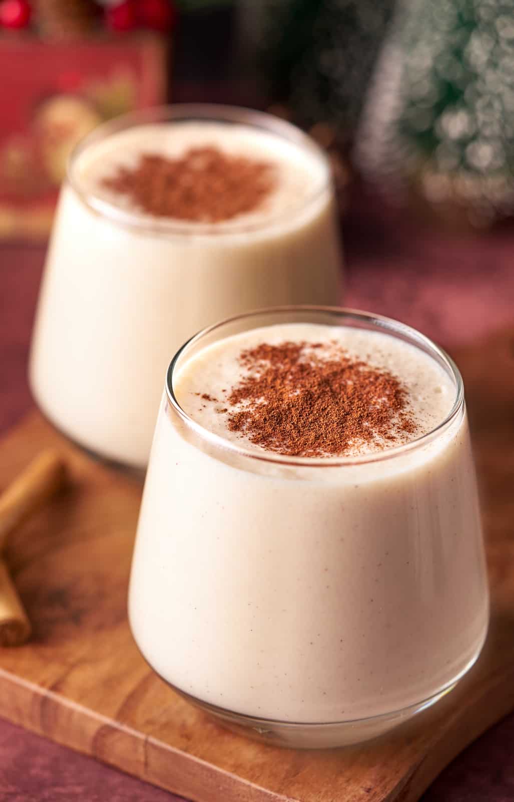 Two glasses of Coquito topped with ground cinnamon.