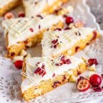 Square image of cut bars on white platter with cranberries.