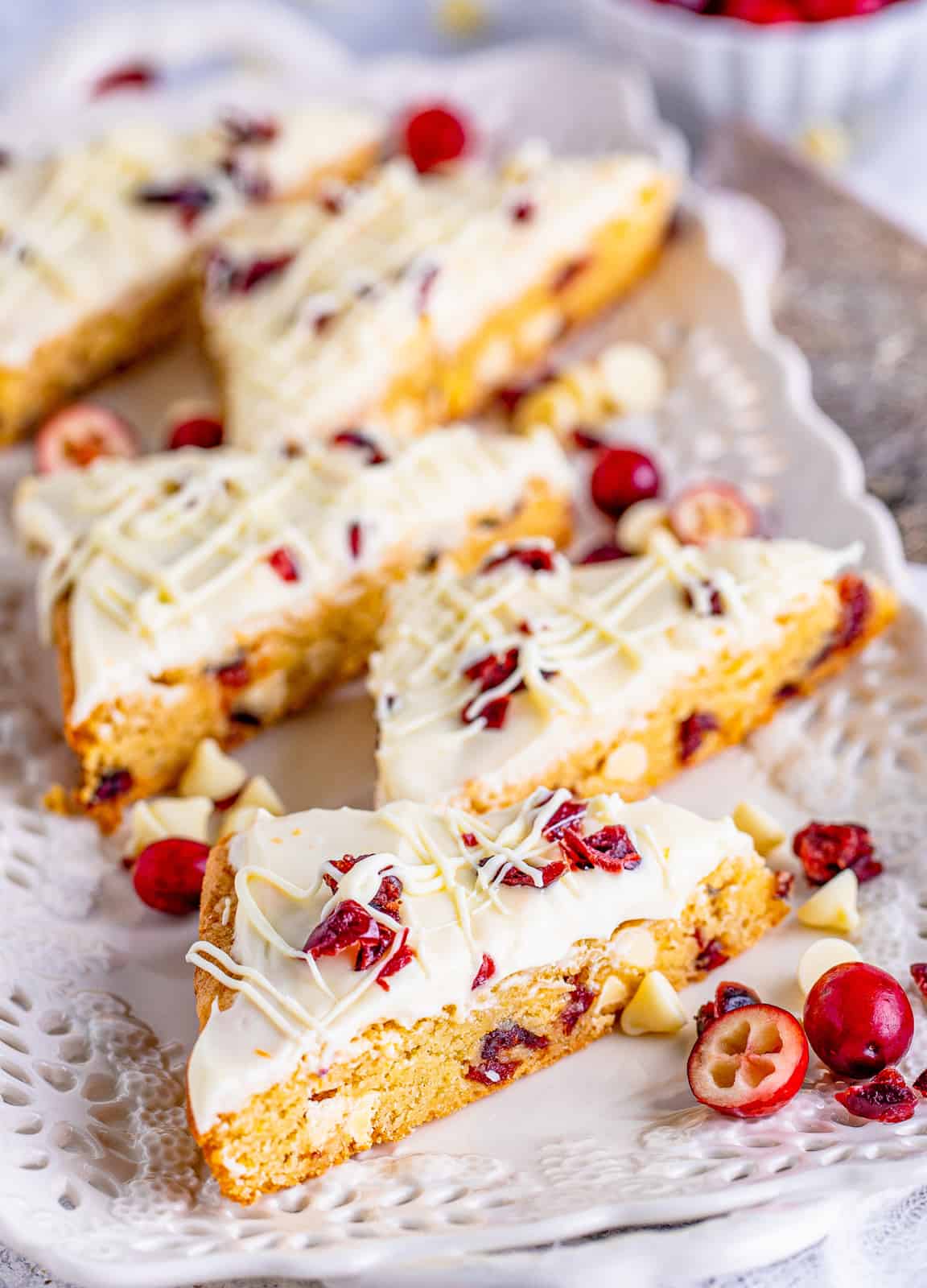 Cut Cranberry Bliss Bars on white platter with cranberries.