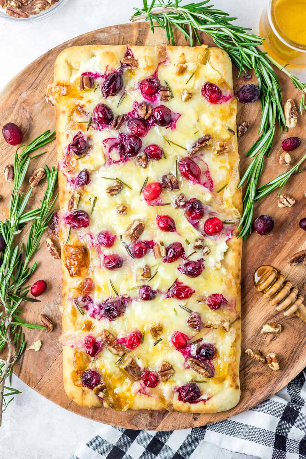 Finished Flatbread on platter with herbs and cranberries surrounding it.