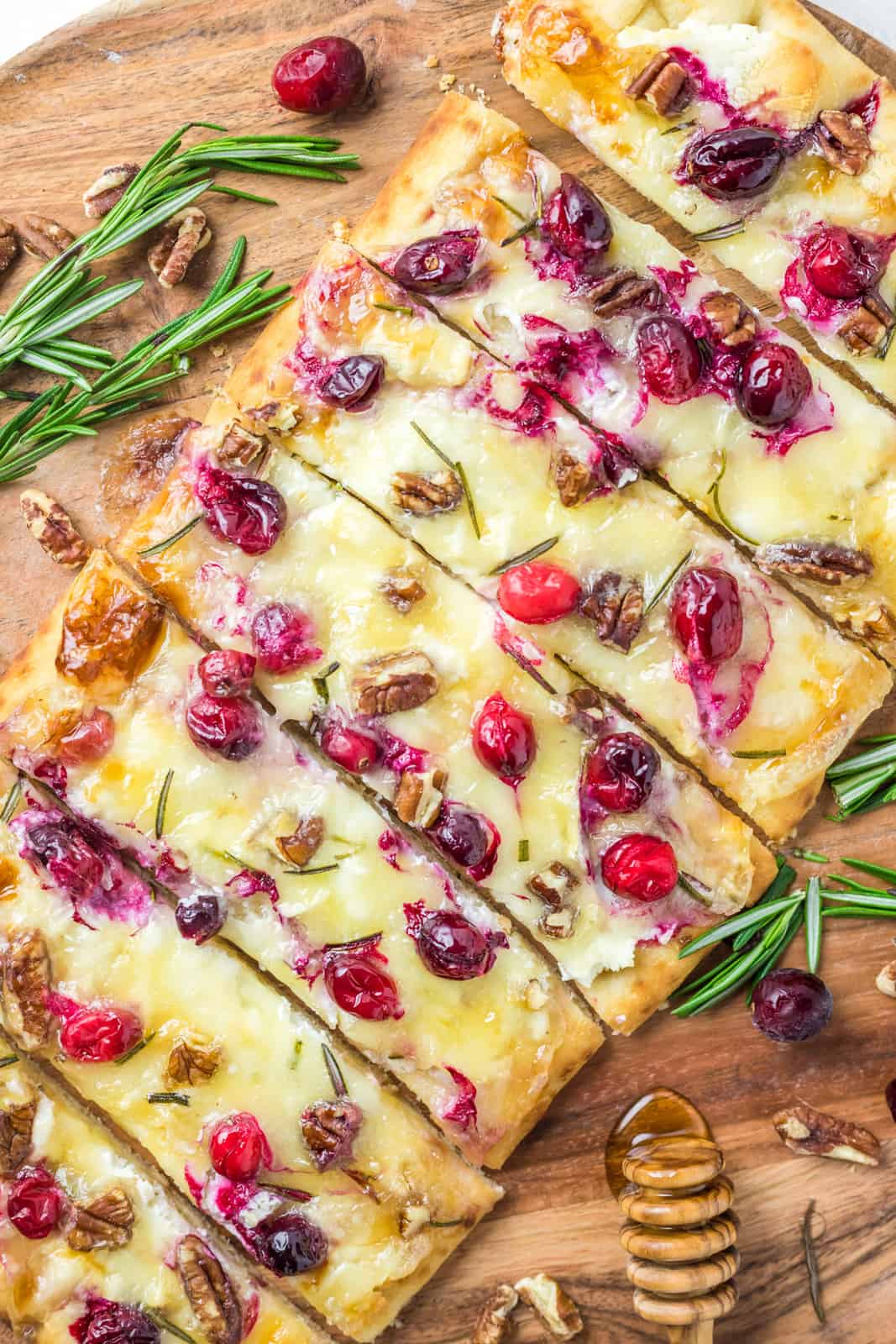 Cranberry Brie Flatbread cut into strips on wooden platter.