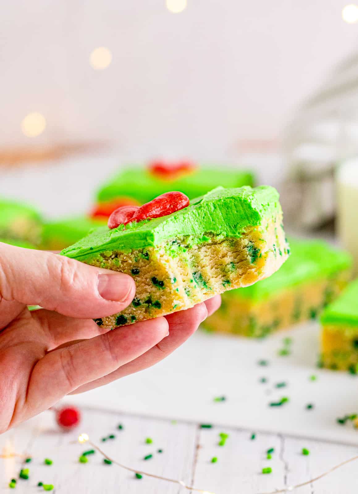 Hand holding up one Grinch Sugar Cookie Bar with bite taken out of it.