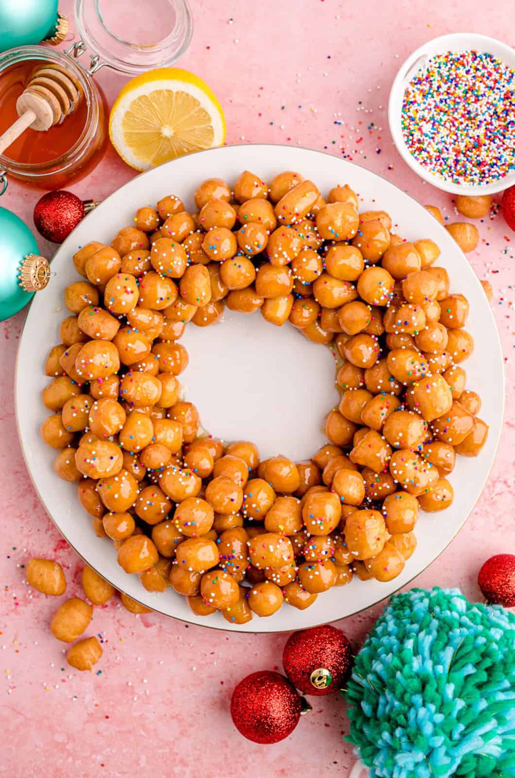 Struffoli on platter with sprinkles in a wreath circle shape.