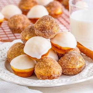 Square image of donut holes on white plate stacked.