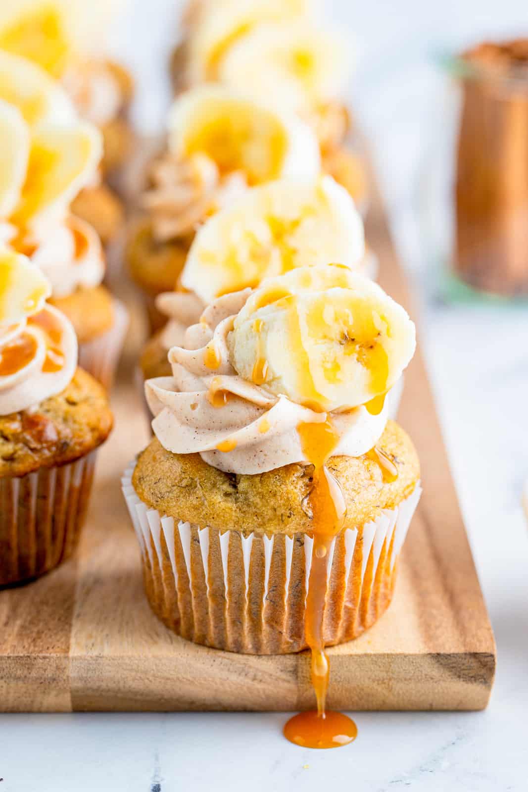 Banana Cupcakes on wooden board with caramel drizzling down side.