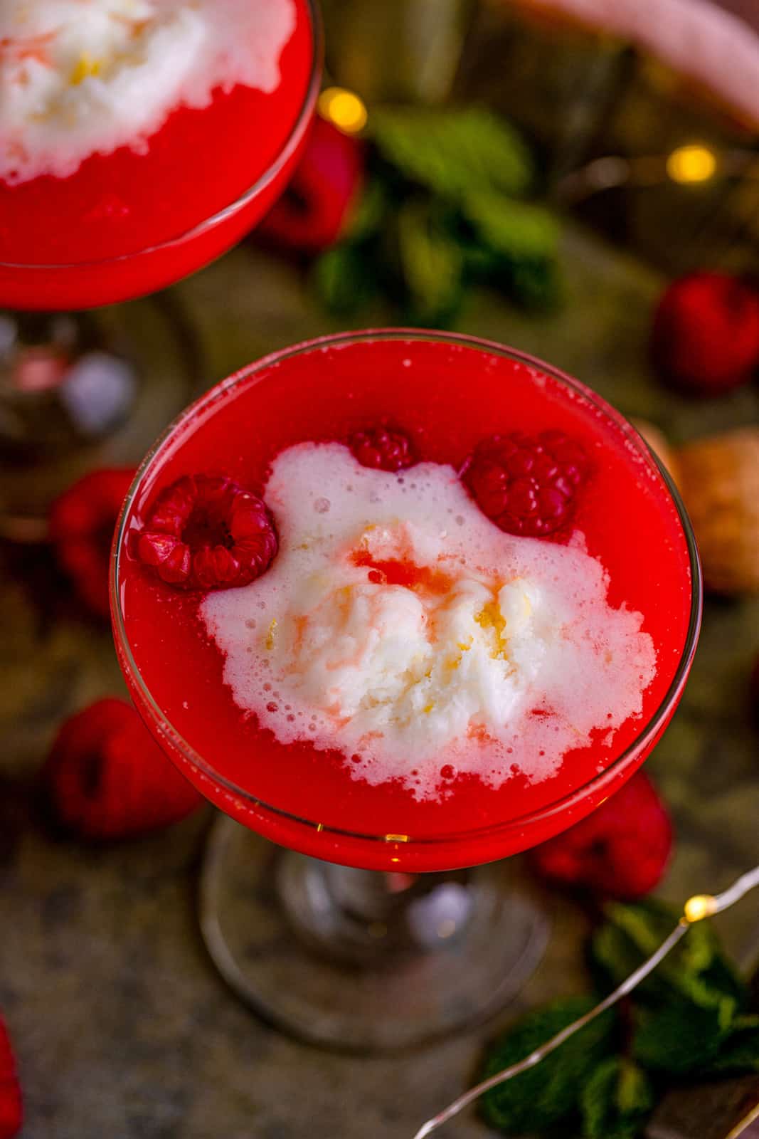 Close up overhead of a glass of Boozy Pineapple Punch with sherbet and raspberries.