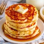 Square image of pancakes stacked with pat of butter and syrup.