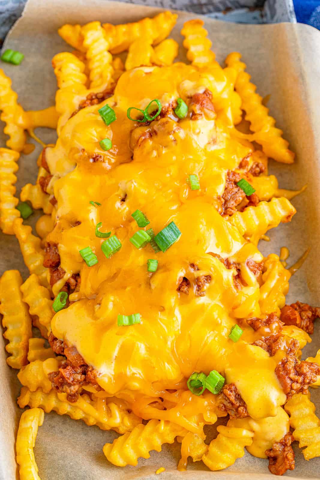 Overhead of Chili Cheese Fries on parchment paper.