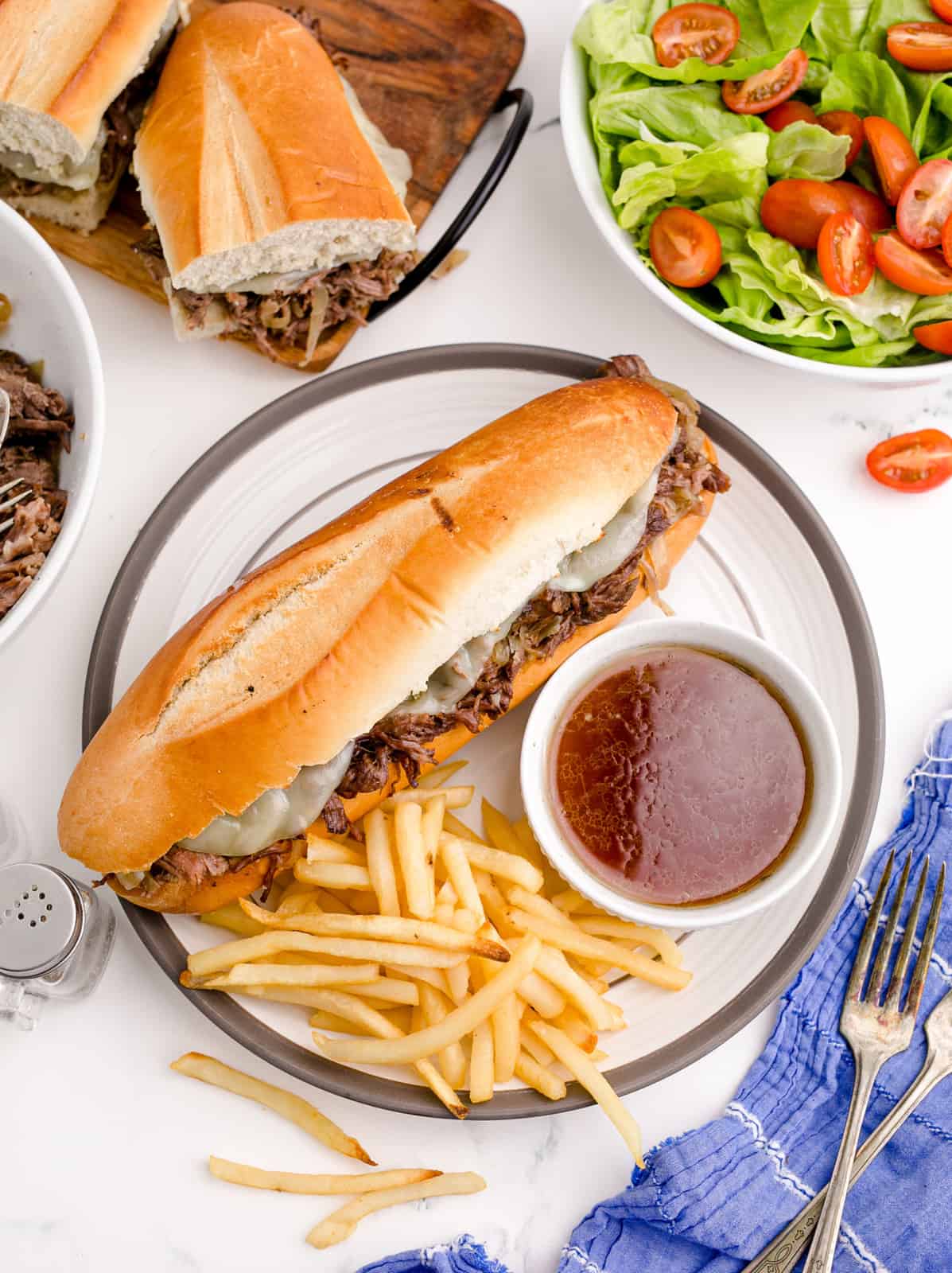 Overhead photo of Crockpot French Dip with french fries and au jus on plate.