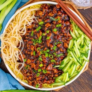 Square overhead image of noodles in bowl with garnishes.