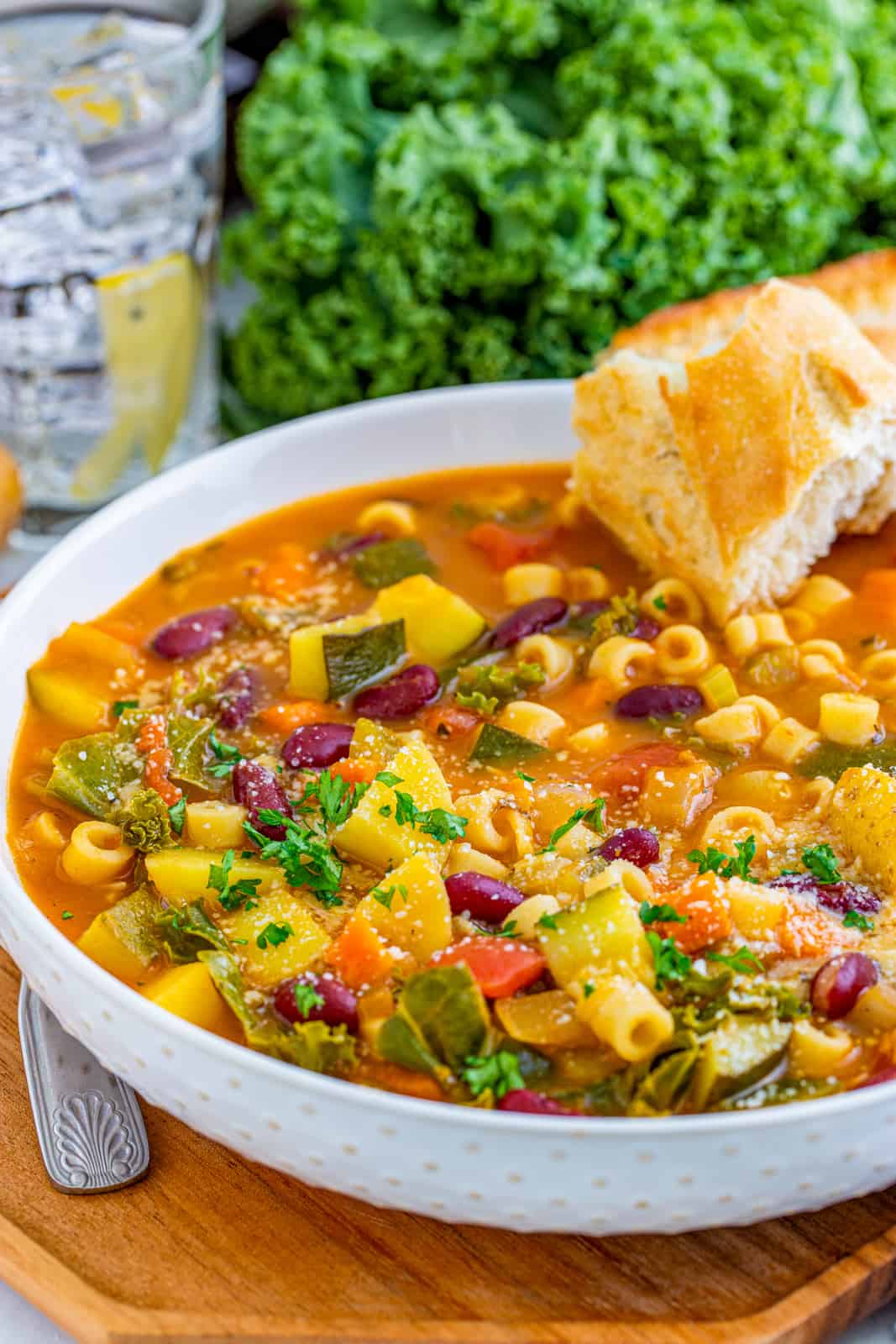 Minestrone Soup Recipe in white bowl with a chunk of bread in bowl.