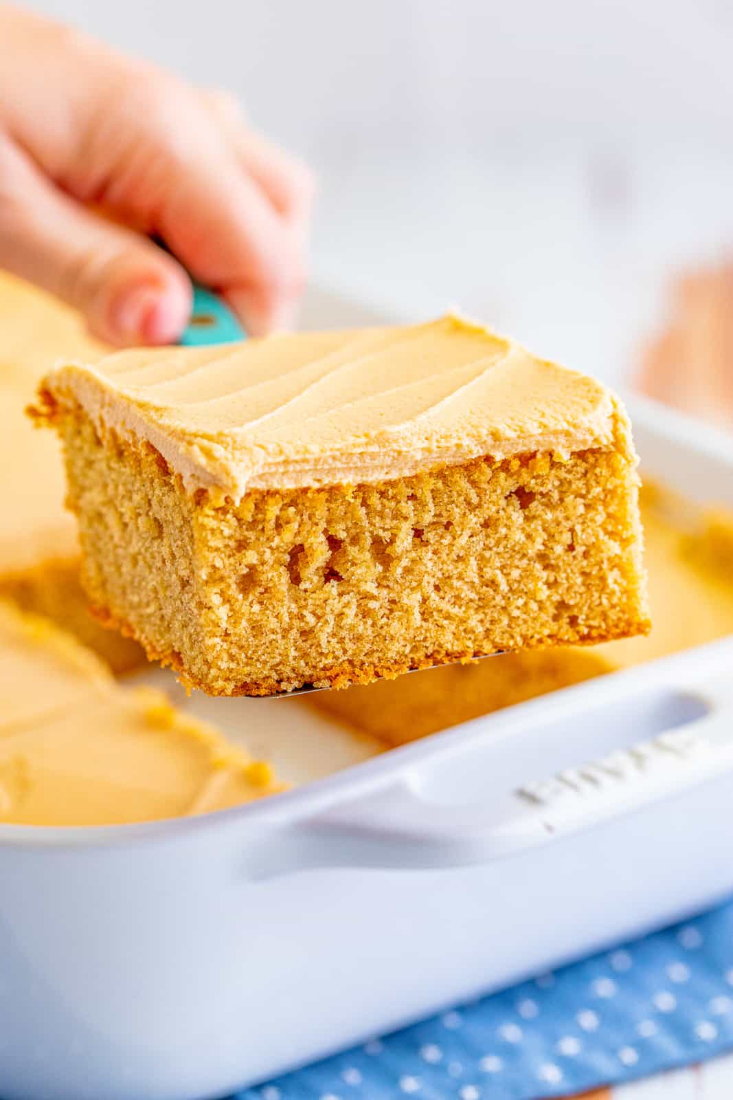 Cake server holding up a slice of Peanut Butter Cake out of baking pan.