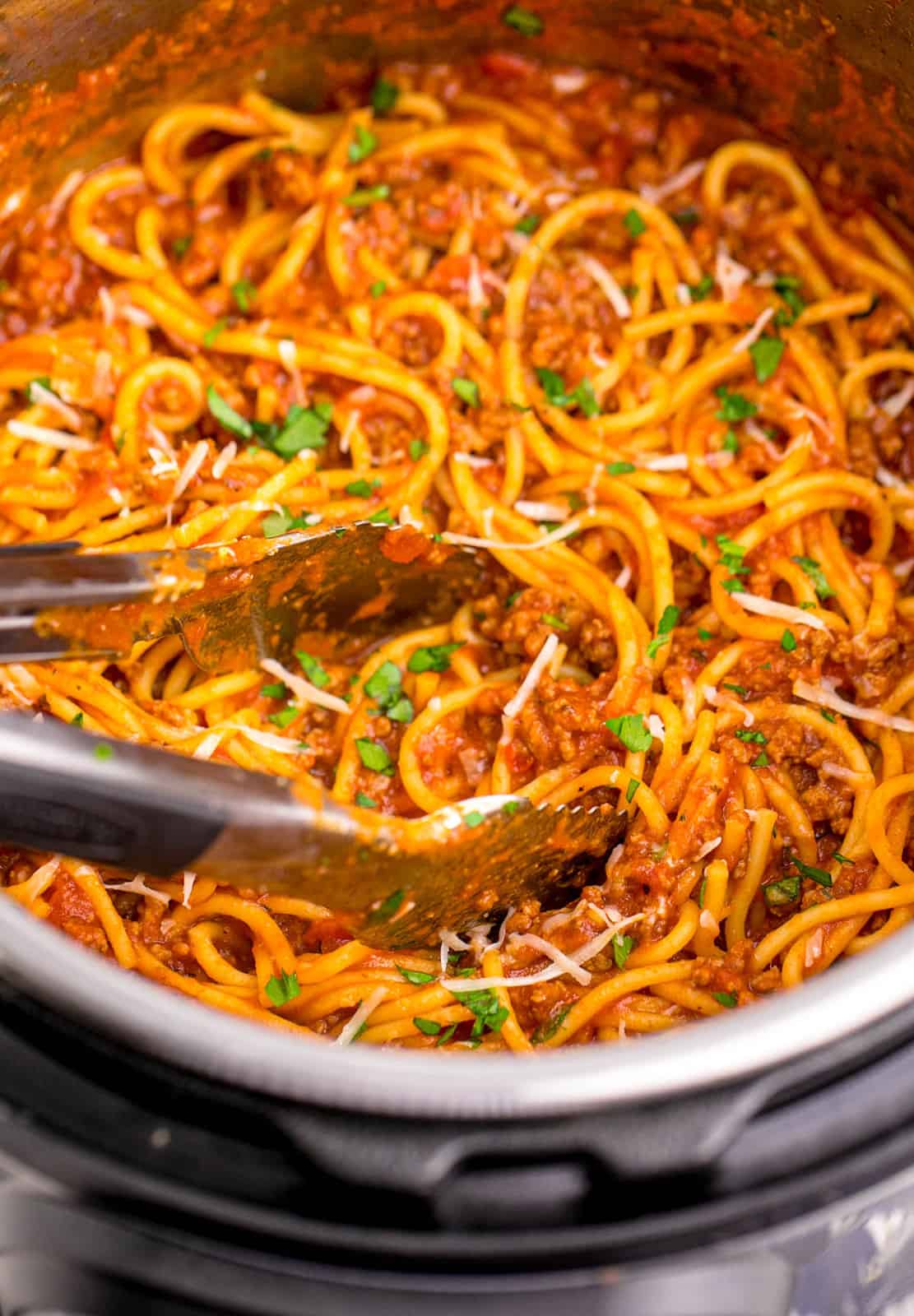 Close up of tongs in instant pot with finished spaghetti.