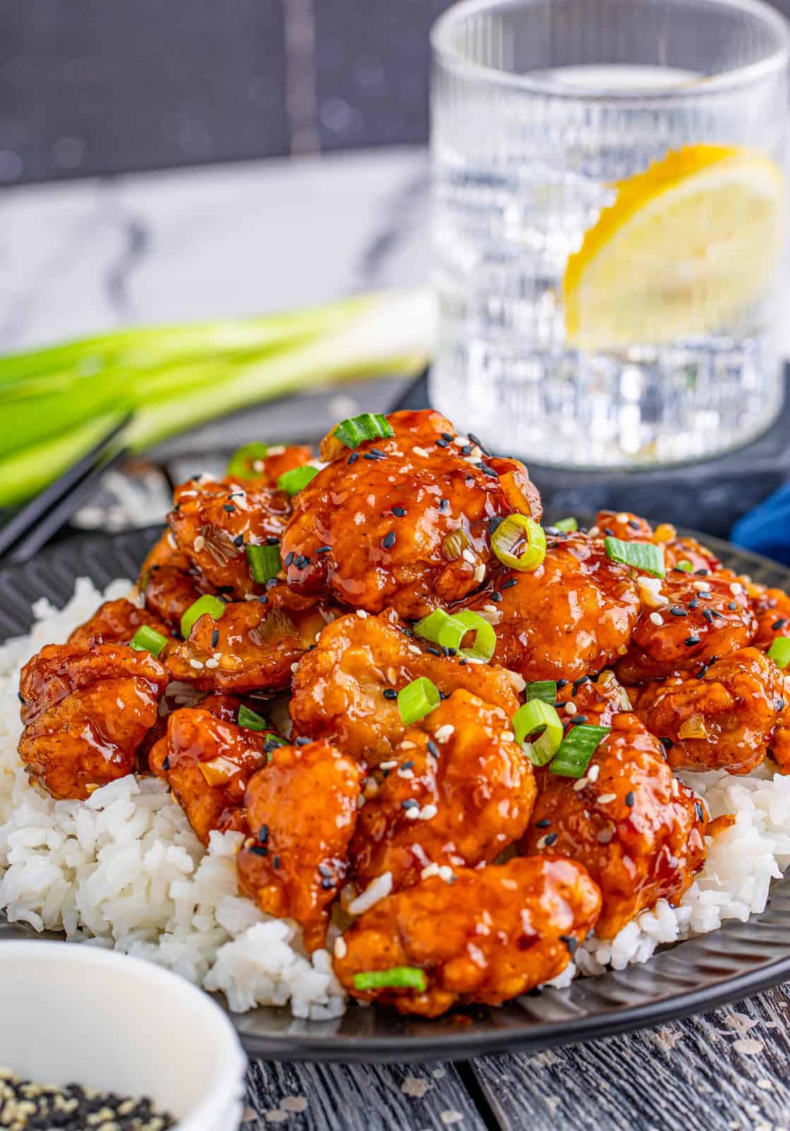Plate with rice and Sesame Chicken Recipe over rice with water in background.