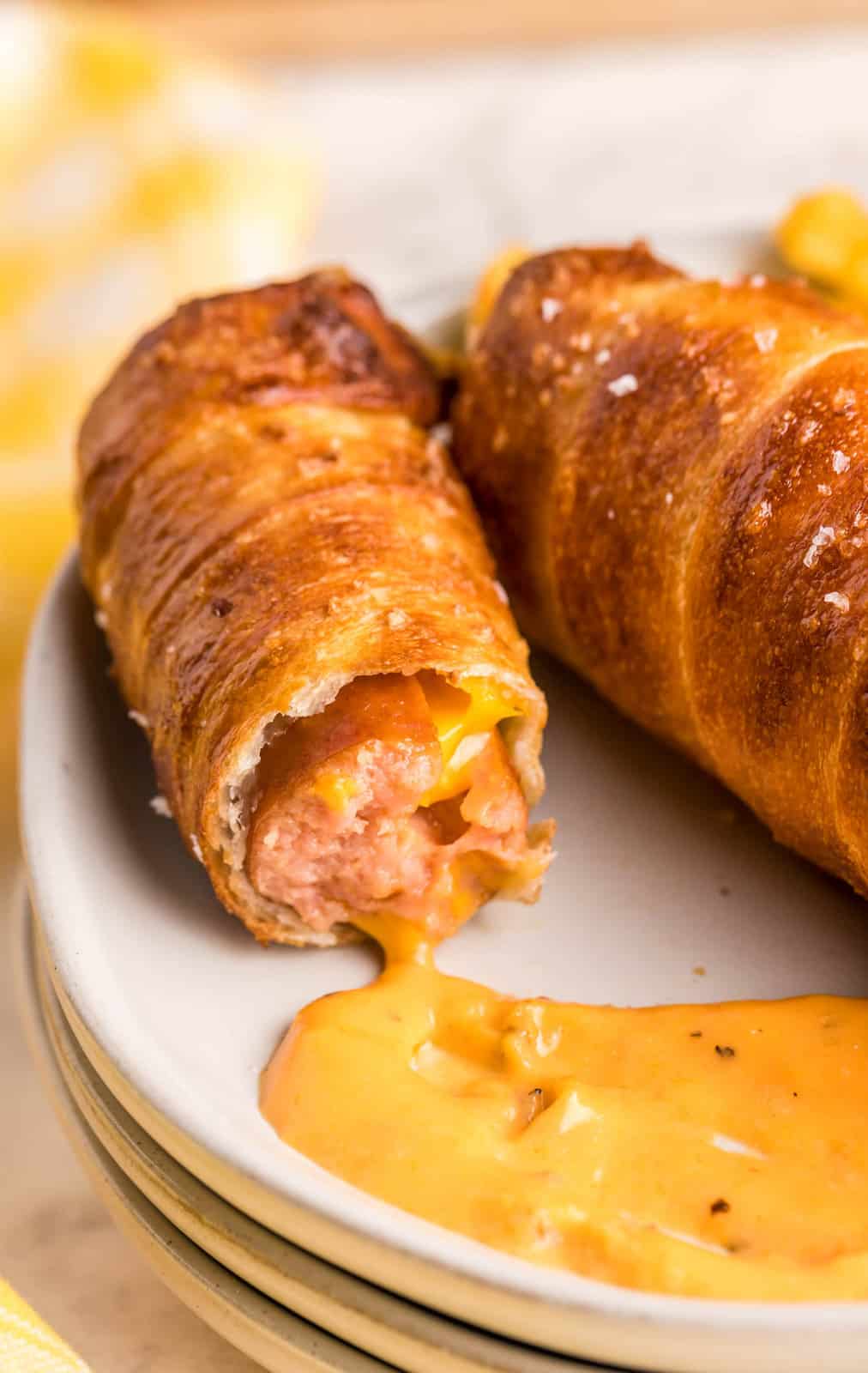 Bite taken out of one Air Fryer Pretzel dog on plate with nacho cheese sauce.