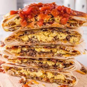 Square photo of Breakfast Crunchwrap cut in half topped with salsa.