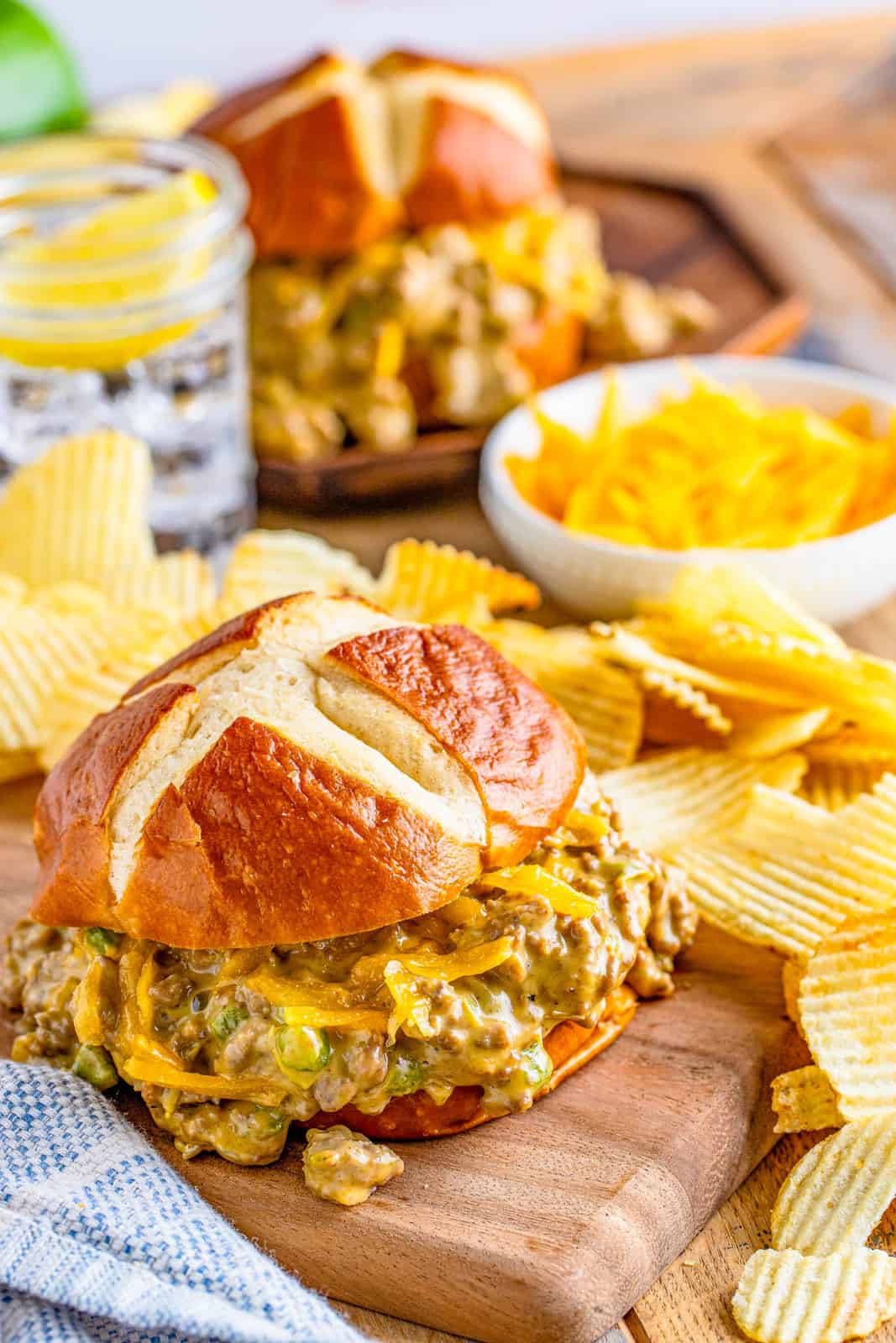 Cheesy Sloppy Joes on wooden board with chips.