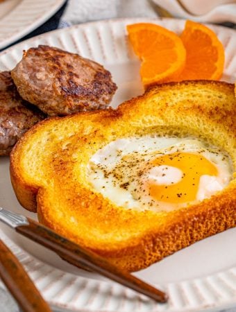 White plate with finished Egg in a Hole with side dishes square image.