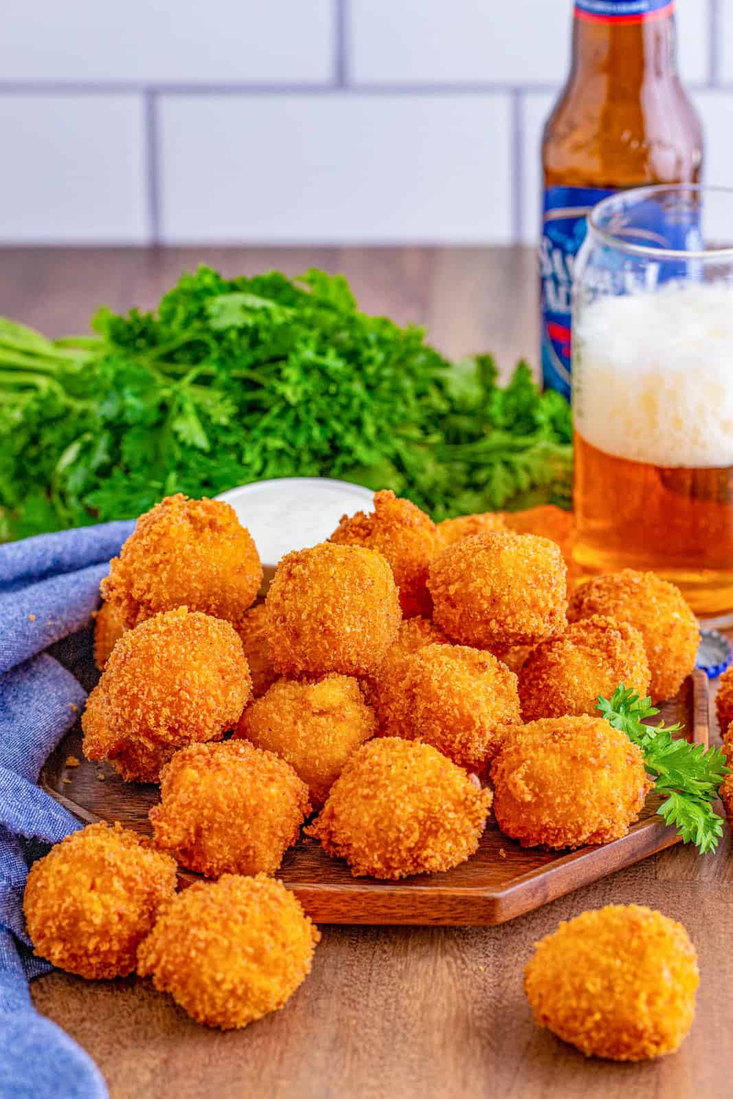 Fried Mac and Cheese Balls on wooden platter with beer in background.