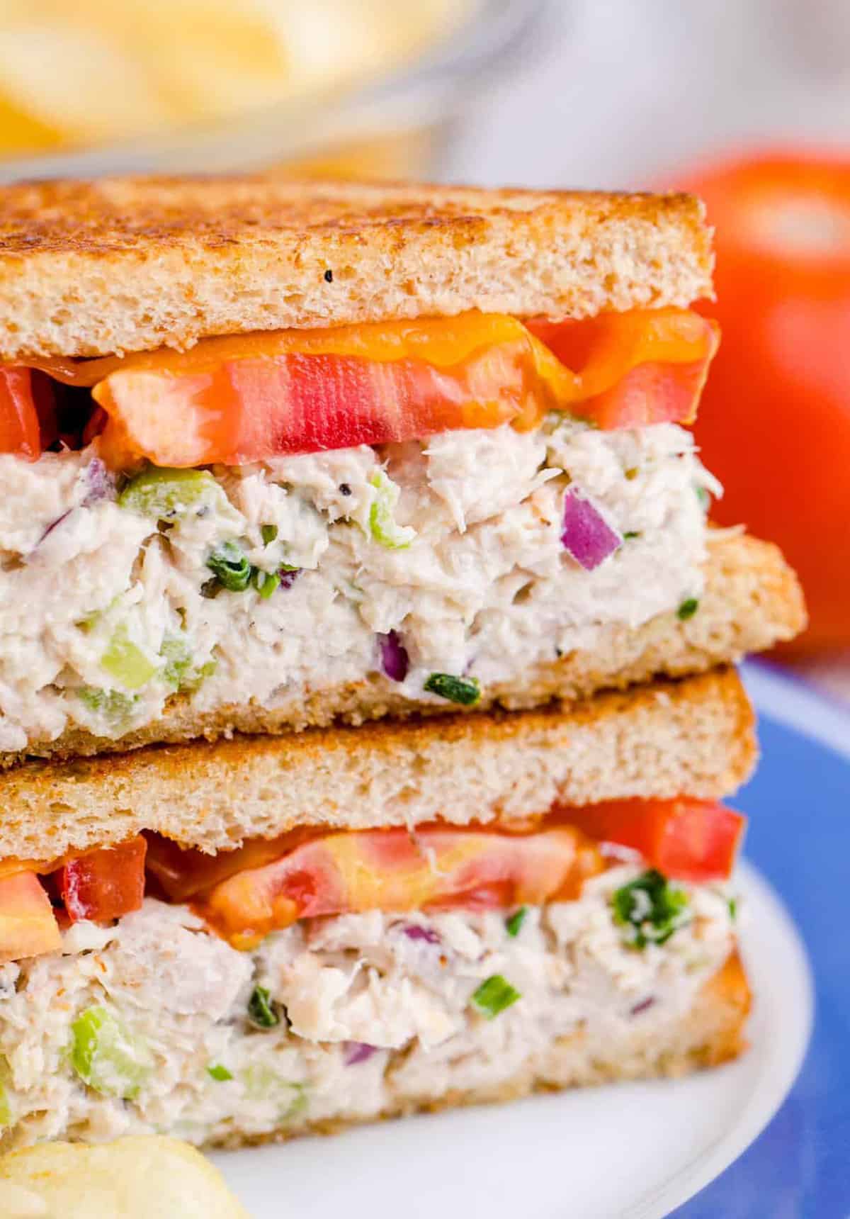 Close up of the Tuna Melt Recipe cut in half and stacked on top of one another on white and blue plate showing the inside.