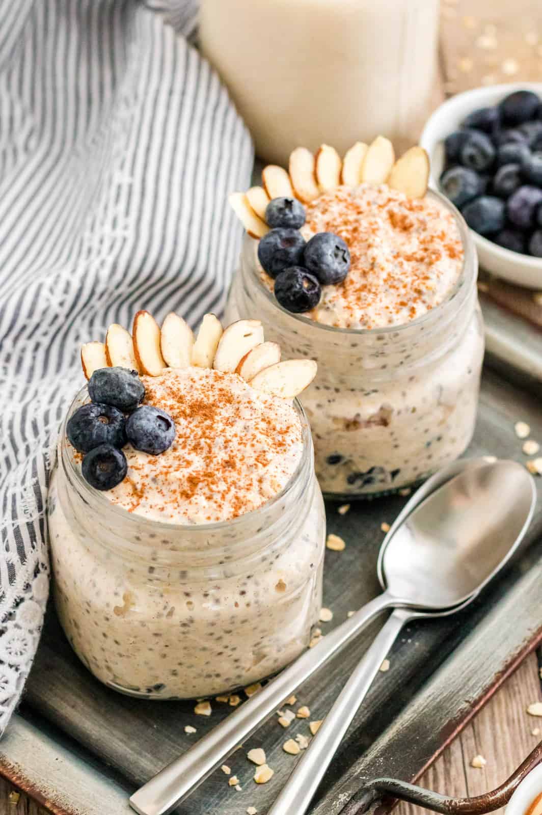 Two jars of Blueberry Overnight Oats garnished on tray.