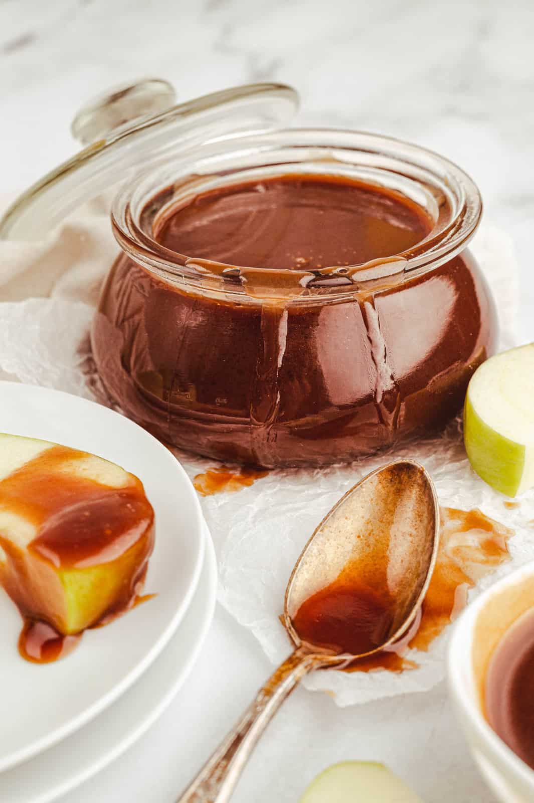 Bourbon Caramel Sauce on apple, spoon and dripping down jar.