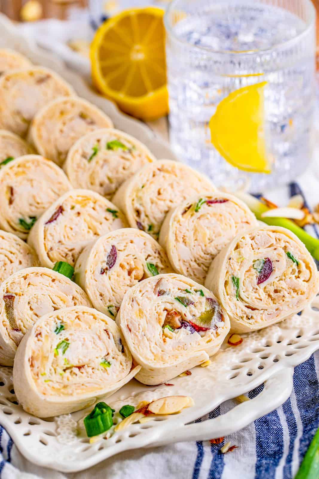 Slice Chicken Salad Pinwheels laying against one another on white platter.