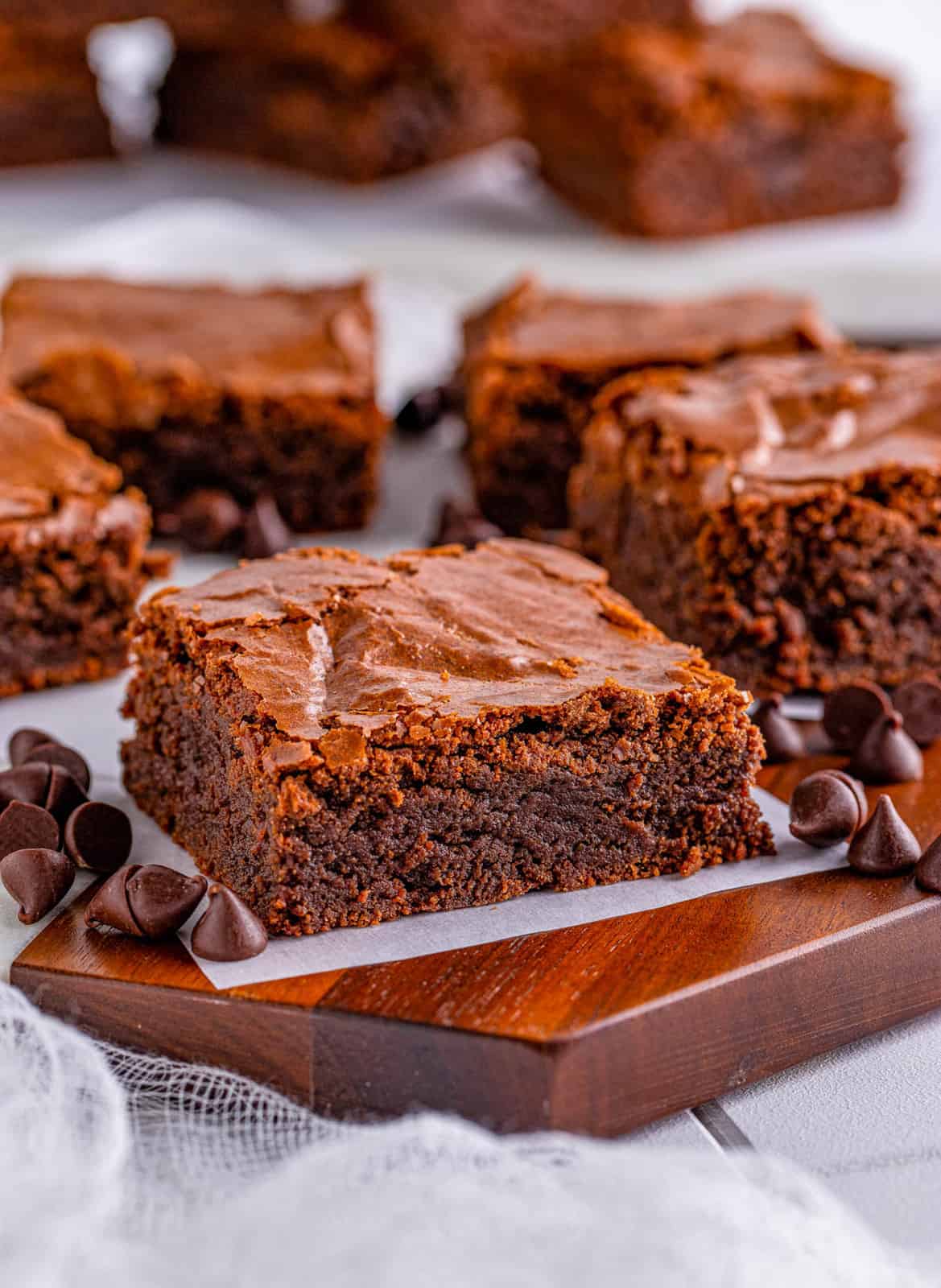 Fudge Brownies on parchment paper on wooden board.