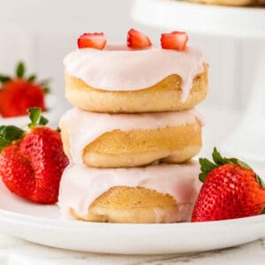 Square image of stacked donuts on white plate.