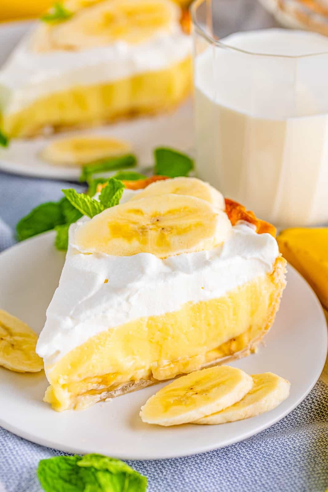 Slice of Banana Cream Pie garnished with banana slices and slices on plate.