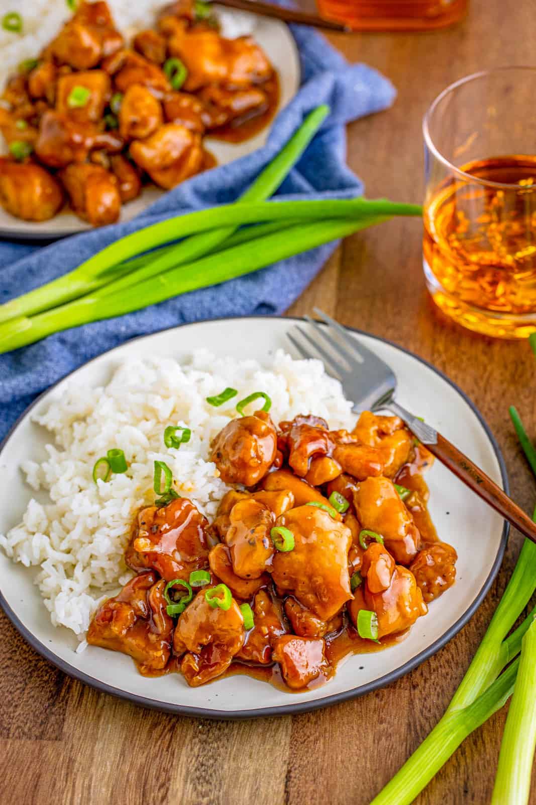 Two plates of Bourbon Chicken with rice and green onions.
