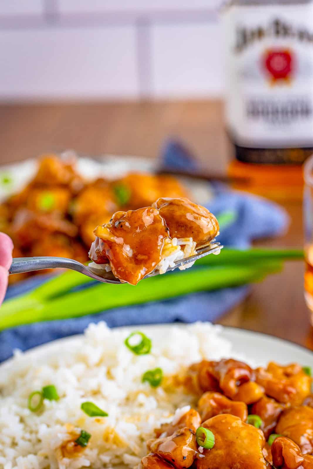 Fork holding up a bite of Bourbon Chicken with rice.