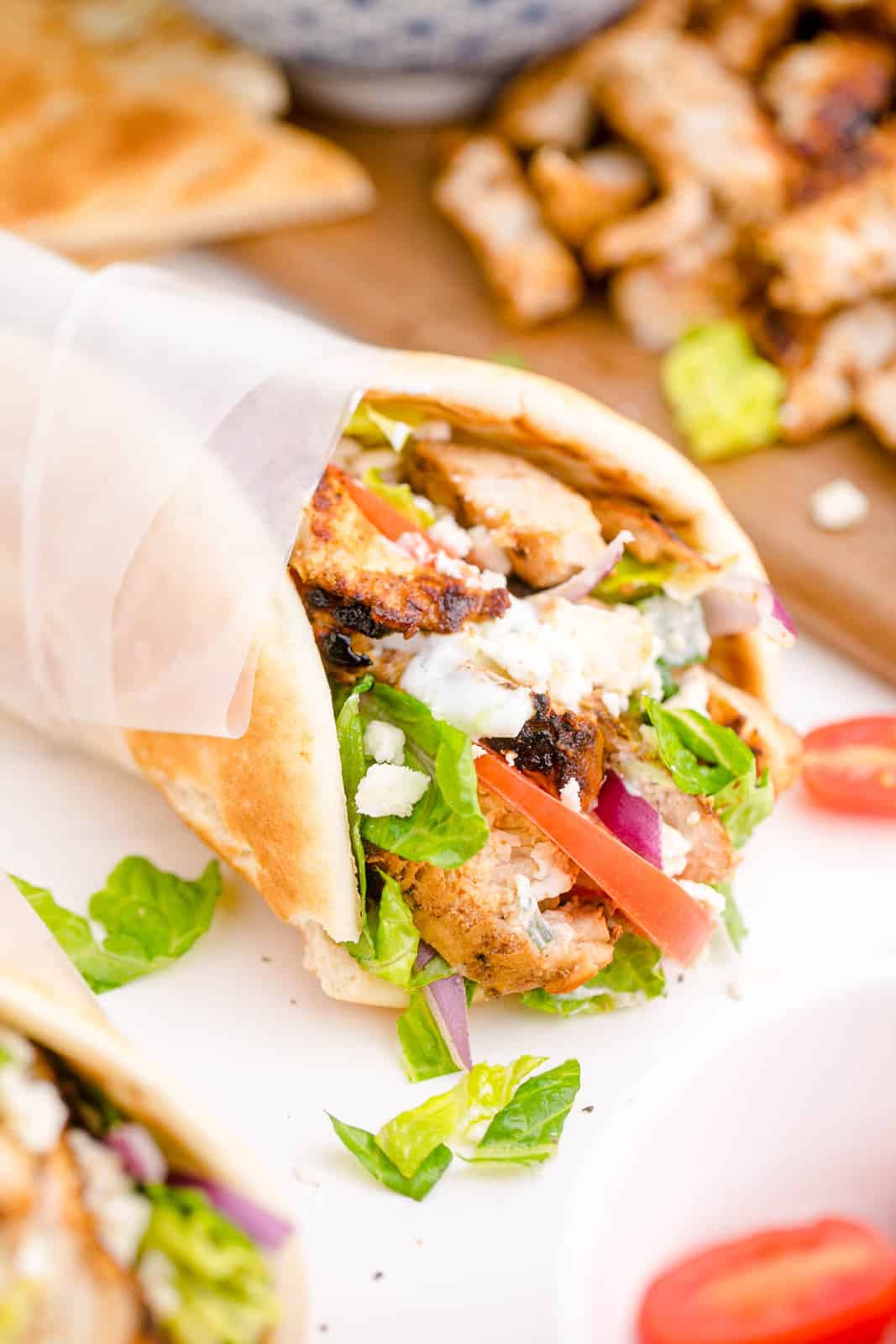 One Chicken Gyro wrapped in parchment paper showing all the filling ingredients.