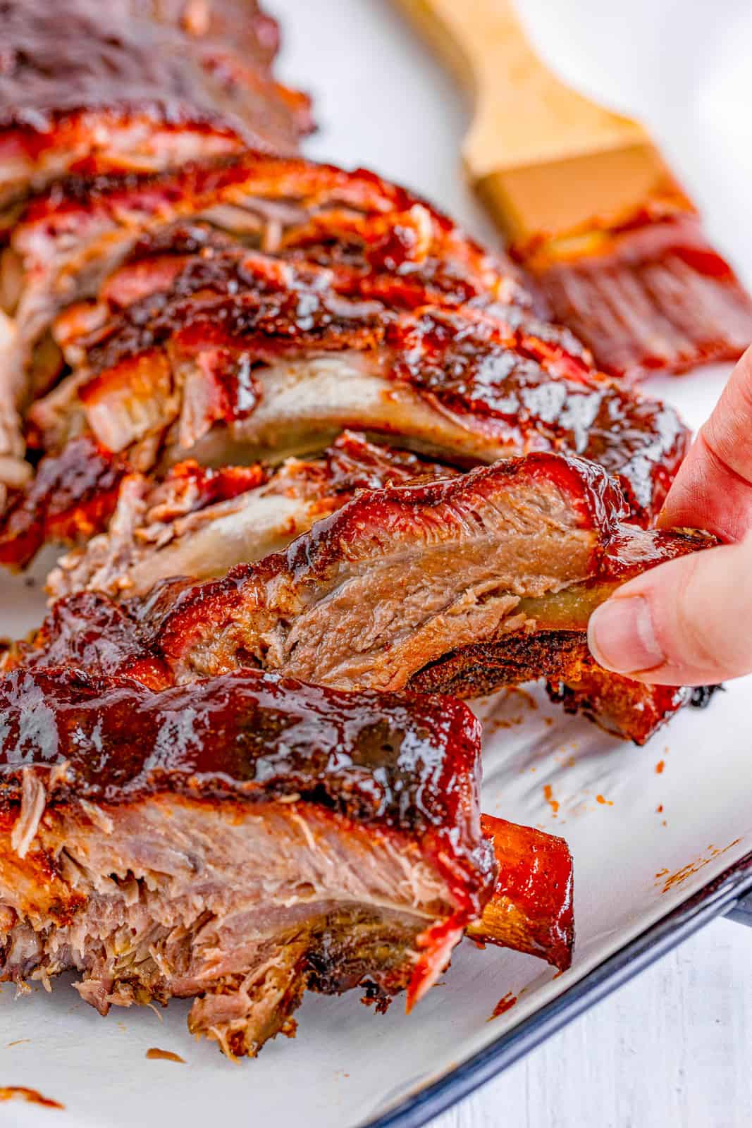 Hand holding up a portion of one Smoke Rib off platter.