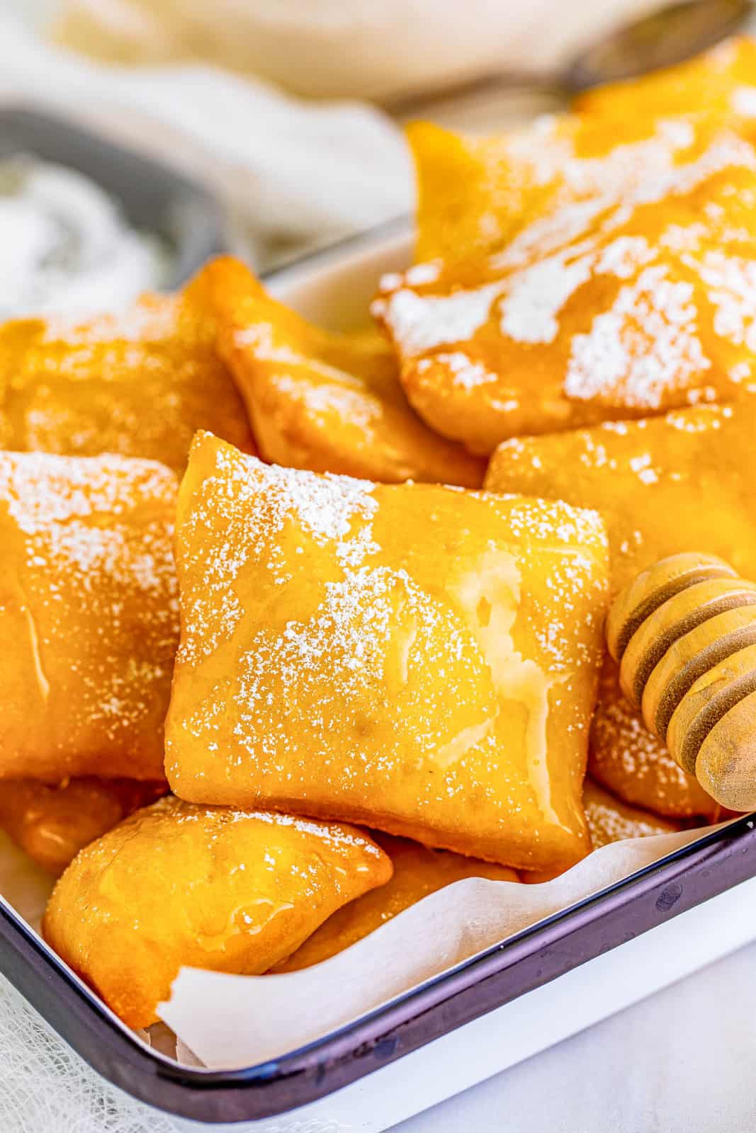 Close up of Sopapillas with honey drizzler showing honey dripping donw one.