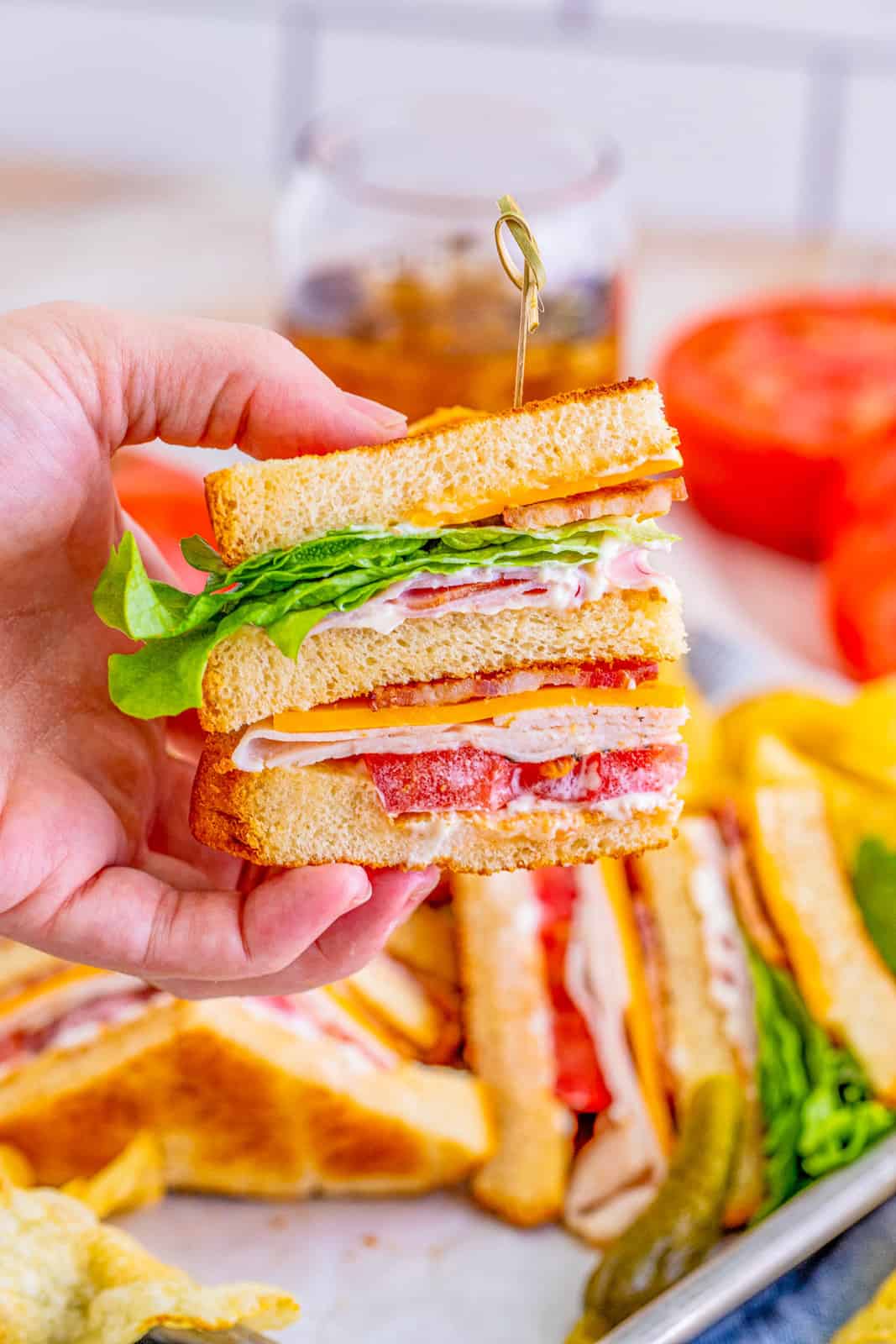 Hand holding up one slice of the Club Sandwich Recipe with tooth pick holding it together.