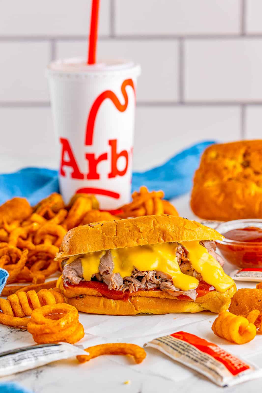 Full meal with Arby's Roast Beef and Cheddar with drink in back.