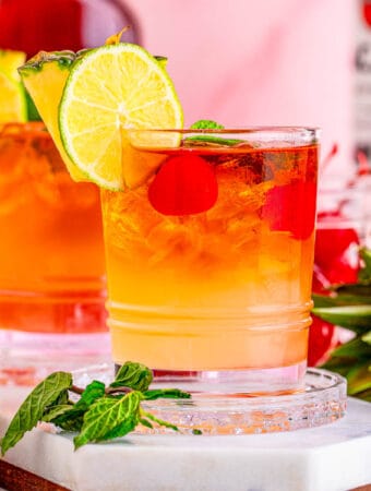 Square image of cocktails on white marble platter with garnishes.