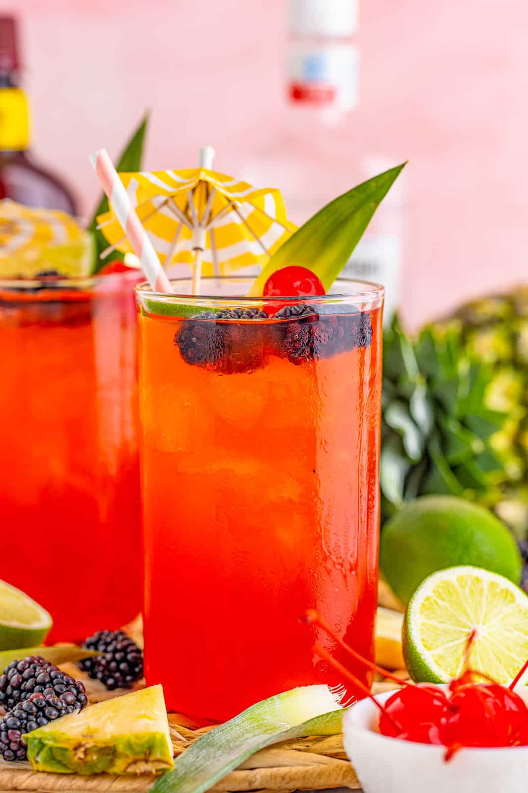 Закройте коктейль Rum Runner с фруктами, окружающими его.