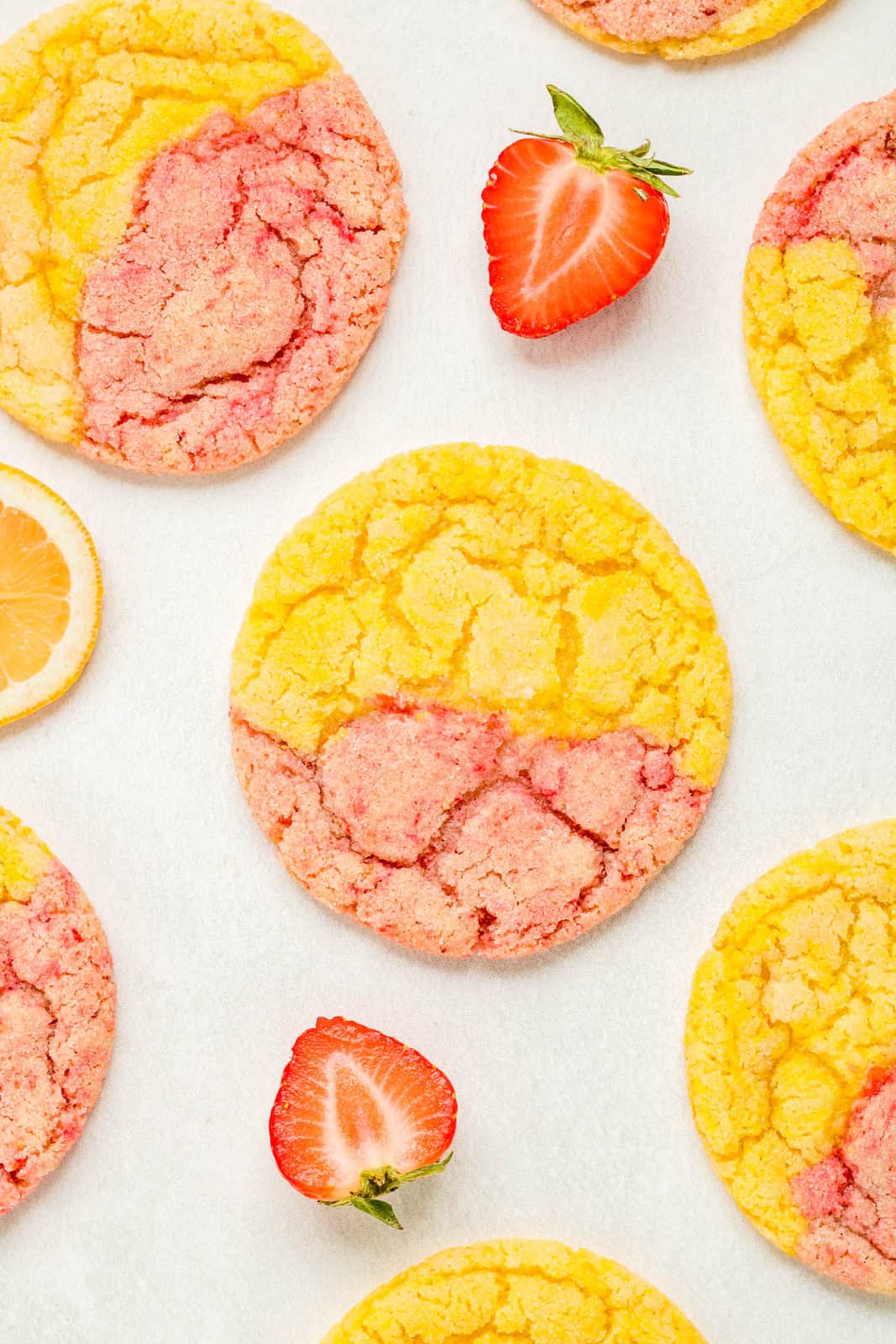Cookies on parchment paper with strawberries and lemons.