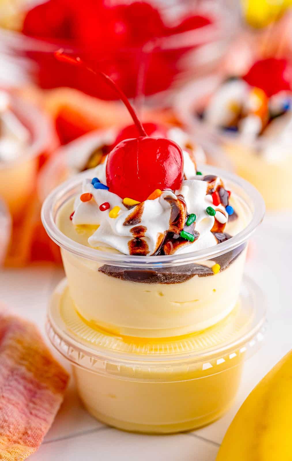 Two stacked Banana Split Pudding Shots on top of one another with top one garnished.