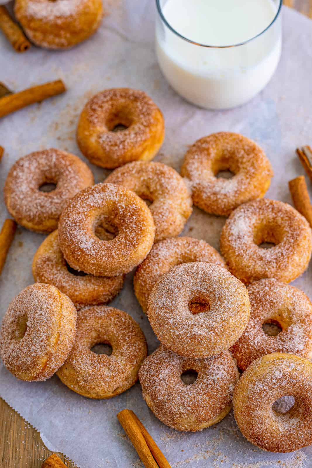 Overhead photo of layered and stacked Cinnamon Sugar Mini Donuts on parchment paper with milk.