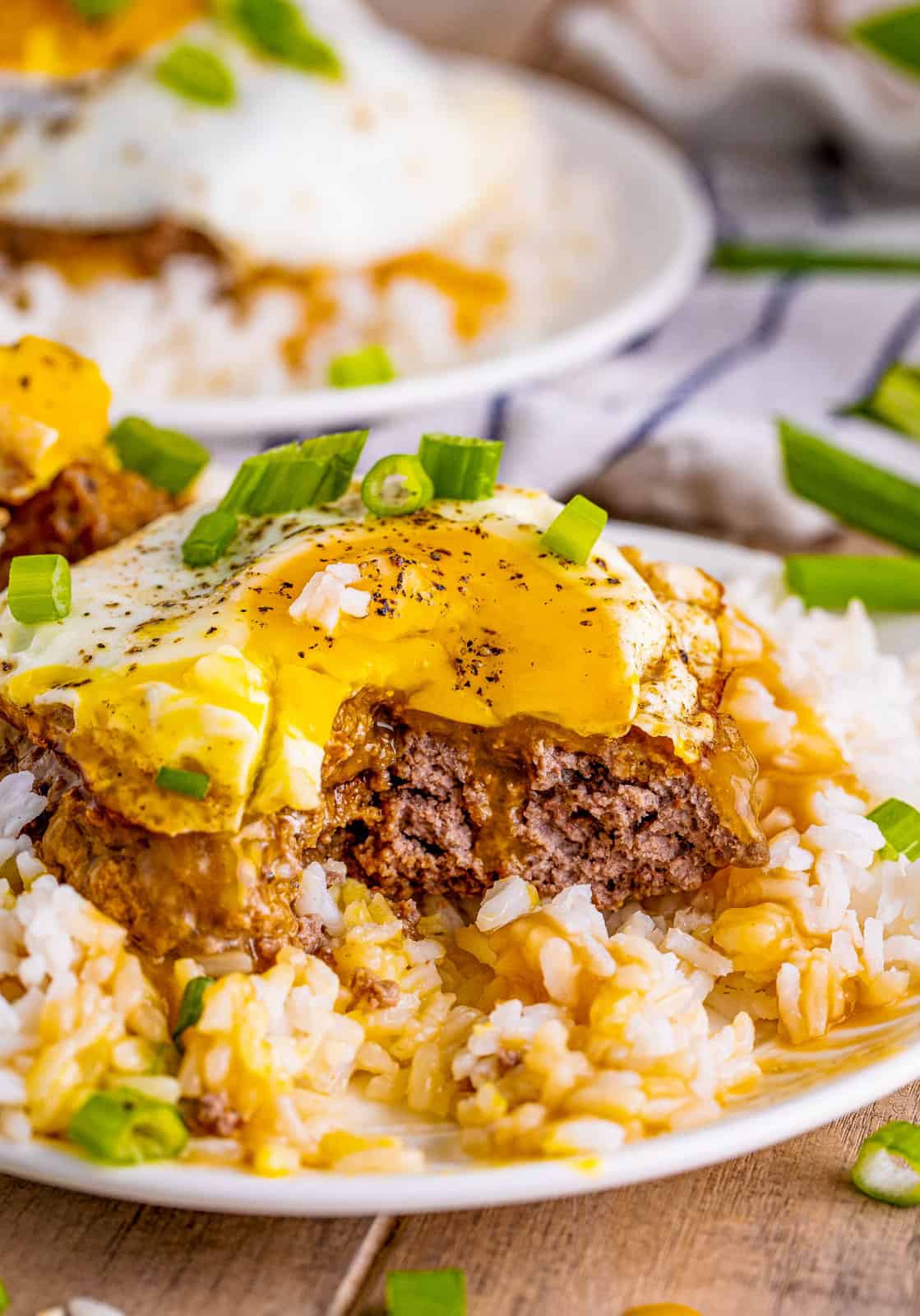 Bite taken out of Loco Moco Recipe showing inside with egg yolk running down.