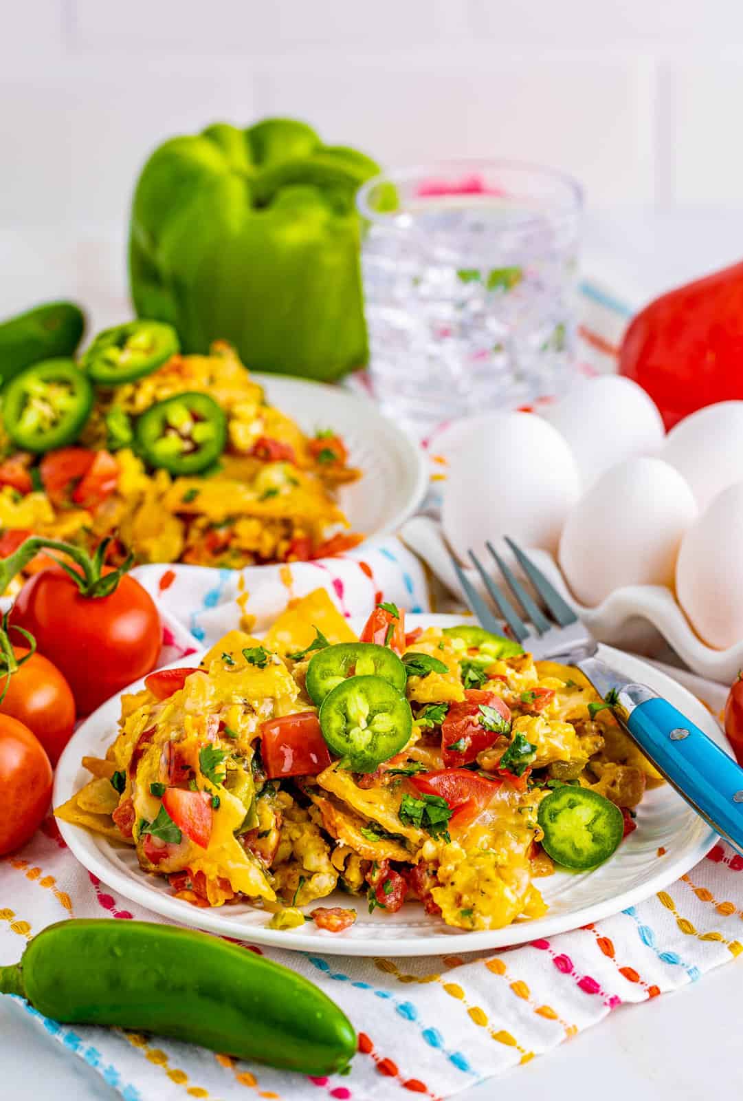 Migas Recipe on two plates with eggs and ingredients in background.