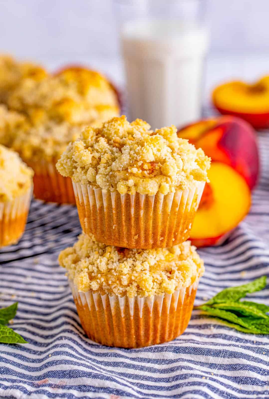 Two stacked Peach Muffins with peaches in background.